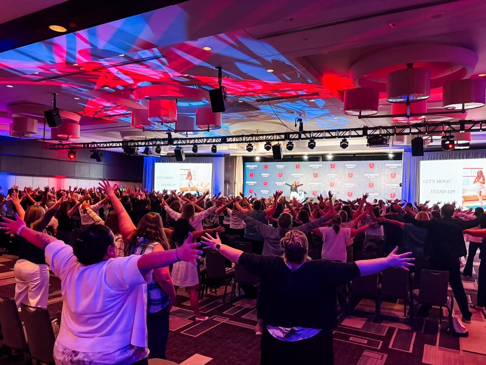 A full conference hall under red and blue stage light